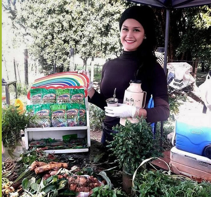 Raquel Rocco - zielarka i influencerka z Paragwaju, przy stoisku ze świeżymi ziołami i suszonymi dodatkami od marki Arcoiris